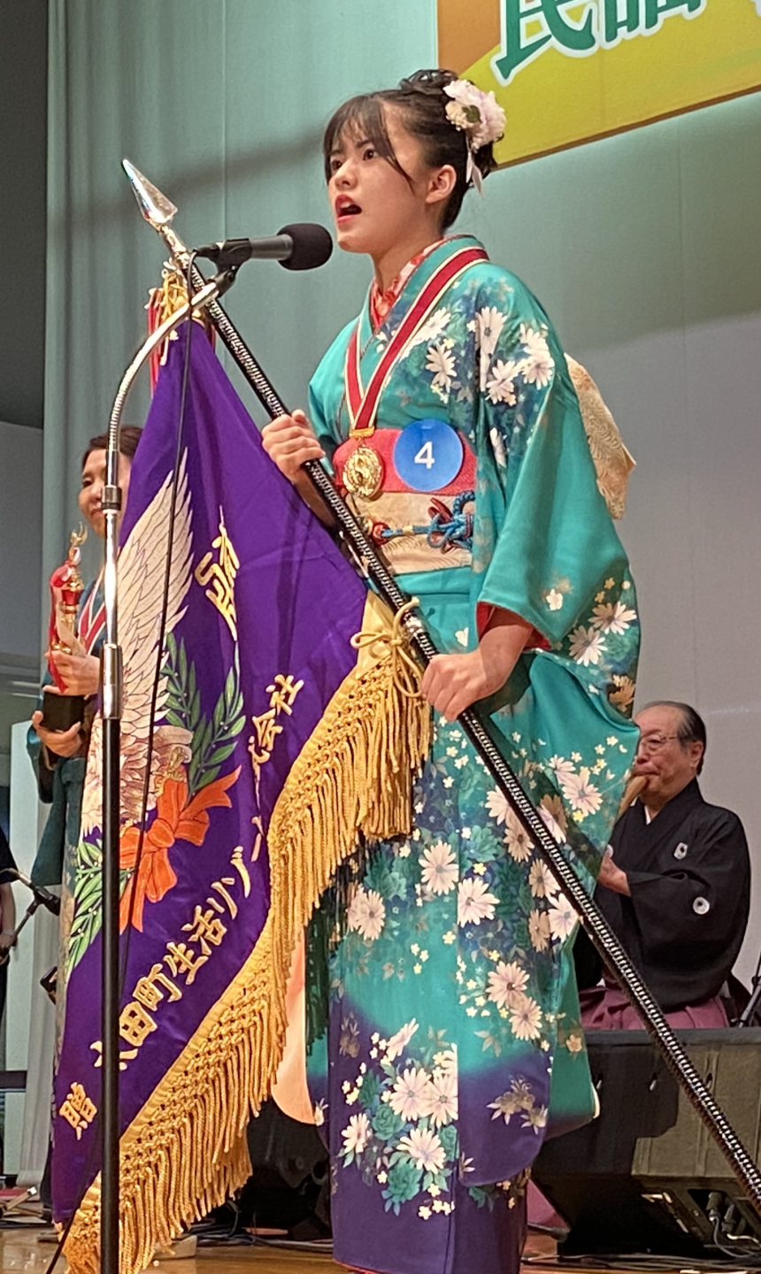 前回大会大賞の部優勝の嵯峨泉稀が優勝旗を持って歌っている